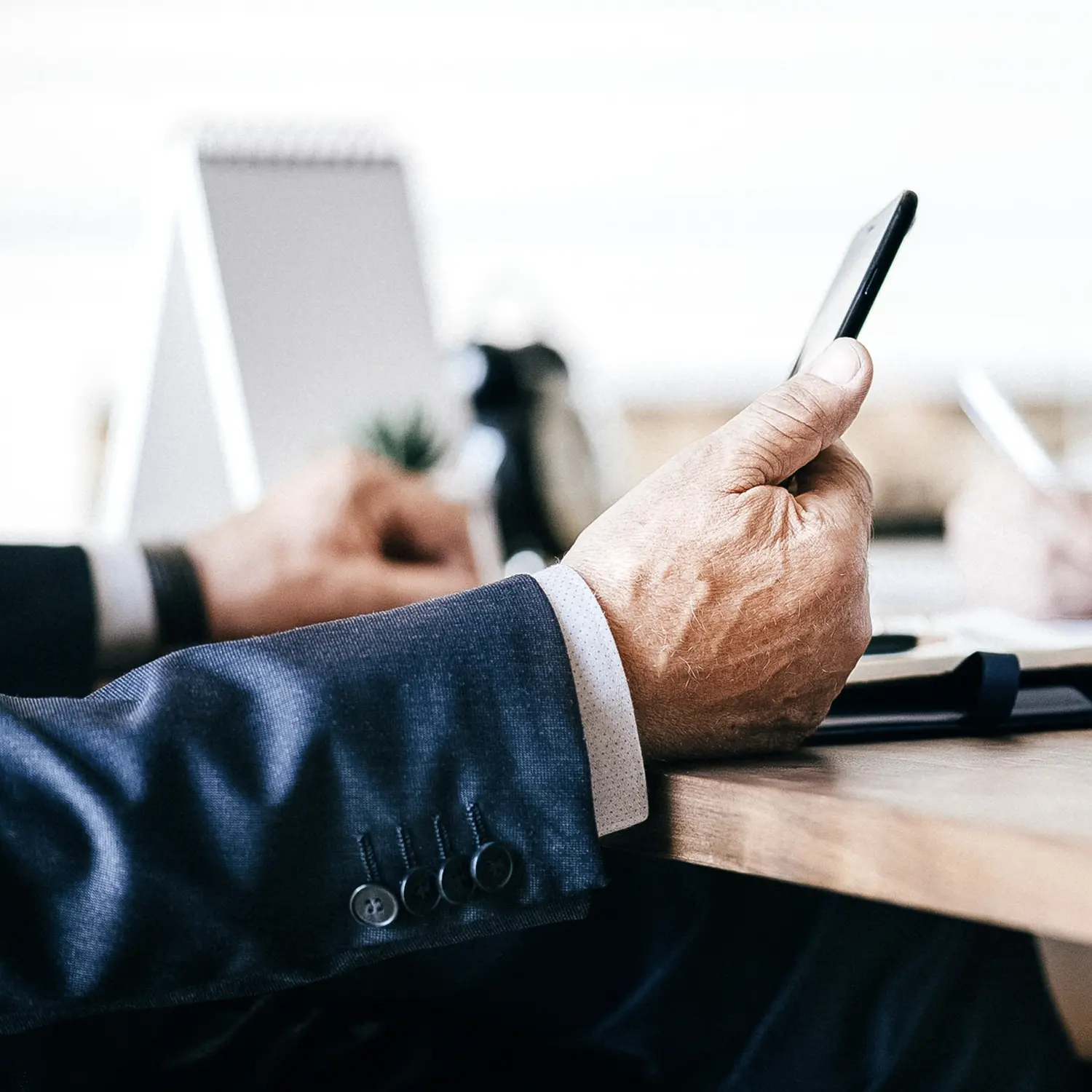 Mann mit Handy in der Hand im Büro. Von der Finomen GmbH